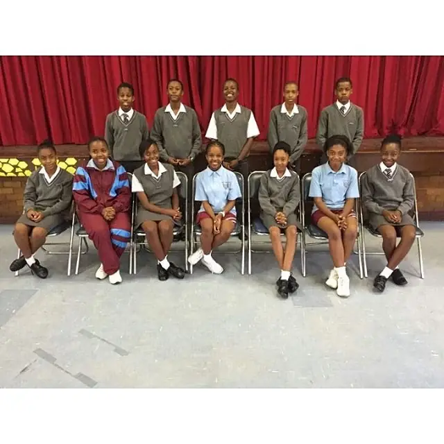 Clapham High School learners in uniform seated on the school stage