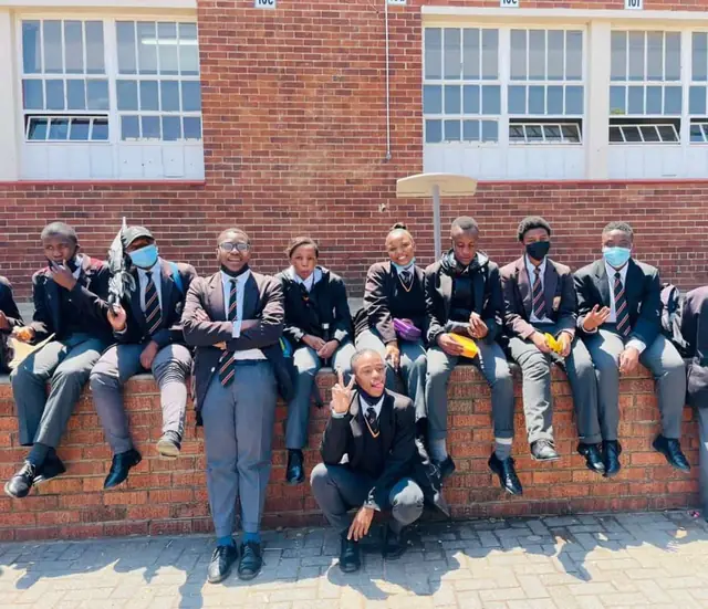 Florida Park High School learners in blazers sitting on a brick wall
