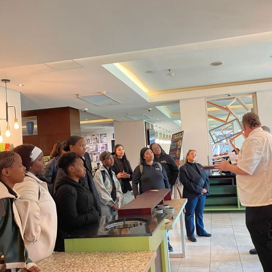 Hospitality Students on an Industry Site Visit College of Cape Town hospitality students listening to a chef during an industry site visit at a hotel kitchen counter