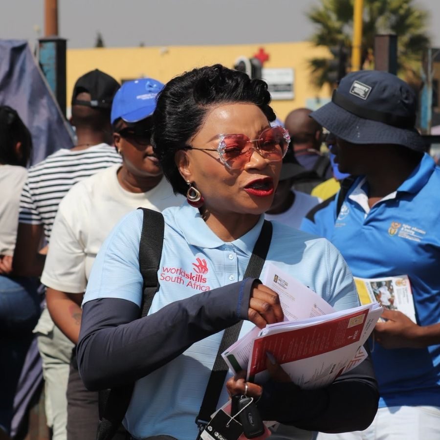 WorldSkills South Africa Representative at College Event A WorldSkills South Africa representative holding documents at an Ekurhuleni West TVET College outdoor event