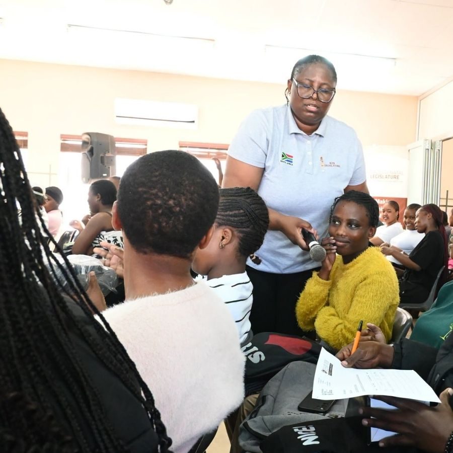 Esayidi TVET College Facilitator Engages Audience Member Esayidi TVET College facilitator holds a microphone for a seated audience member to speak during a public engagement session.
