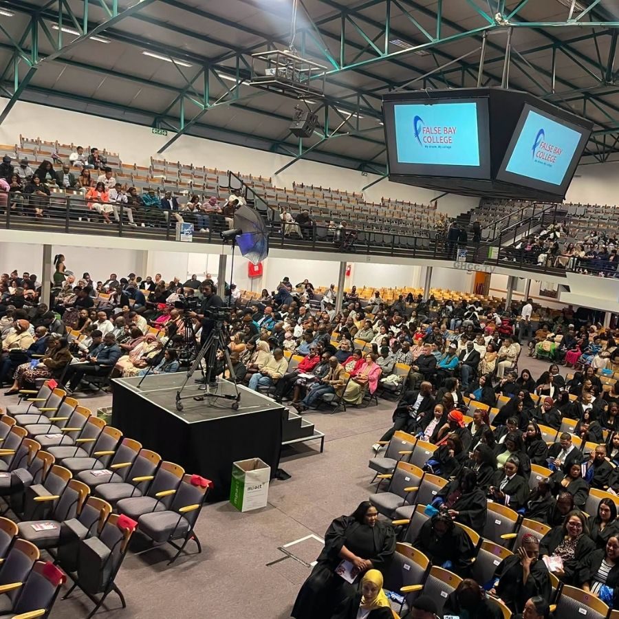 False Bay TVET College Graduation Ceremony Auditorium Packed False Bay TVET College graduation hall with graduates in black gowns and the college logo on screen.