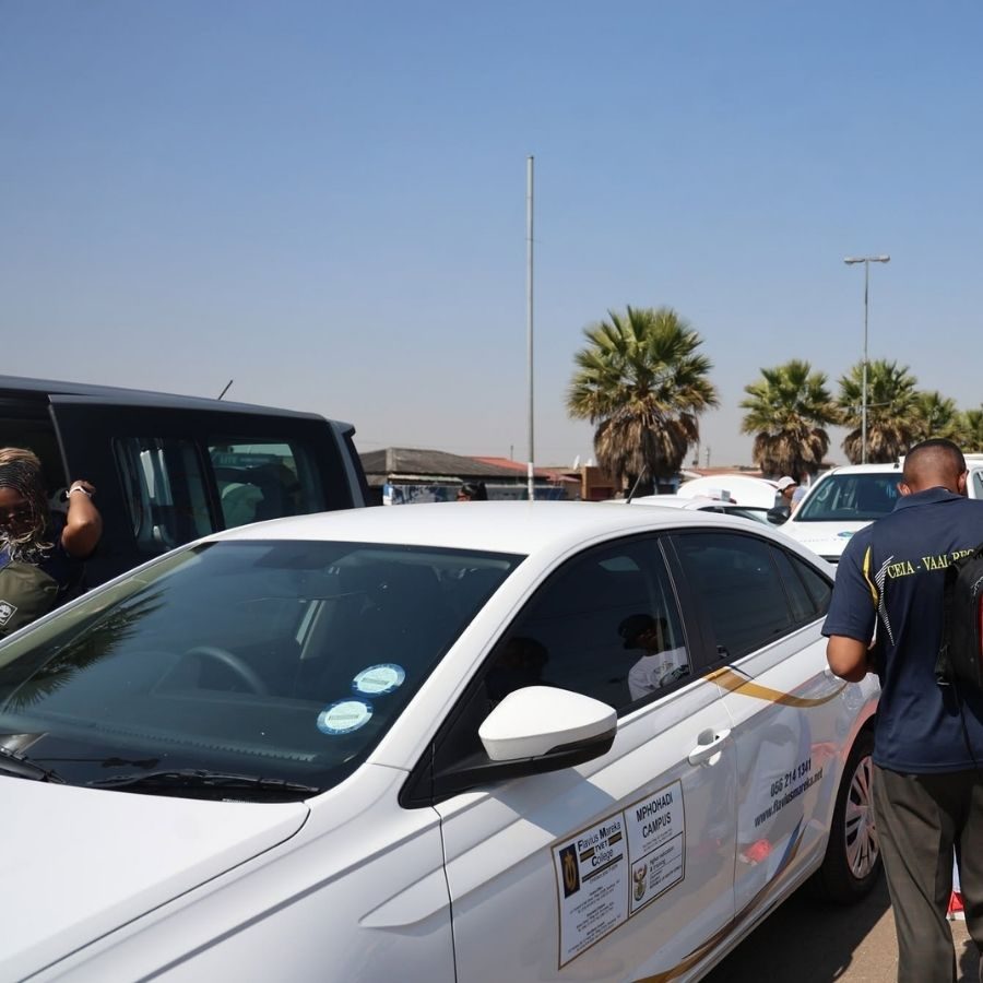 Attendees walk past a Flavius Mareka TVET College branded vehicle at a regional TVET college event.