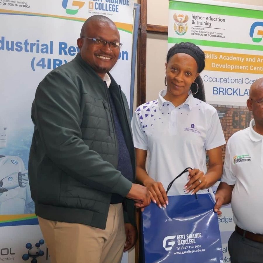 Gert Sibande TVET College Skills Academy Handover Gert Sibande TVET College representative handing over a branded gift bag in front of Skills Academy banners.