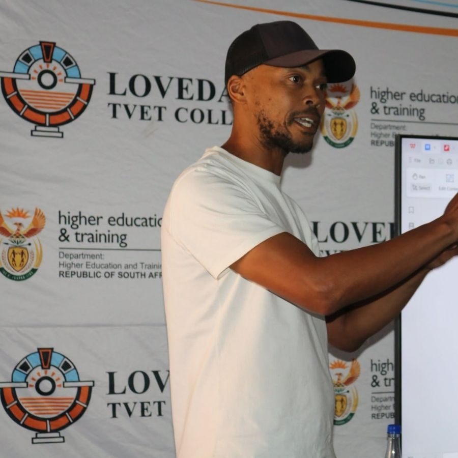 Lovedale TVET College Presenter at Training Session Man in cap pointing at a screen while presenting in front of a Lovedale TVET College and Department of Higher Education backdrop