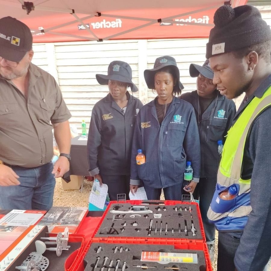 Maluti TVET College Students at Fischer Tools Demonstration Maluti TVET College students in overalls and hats looking at a fixings and fastenings display at a Fischer-branded expo stand