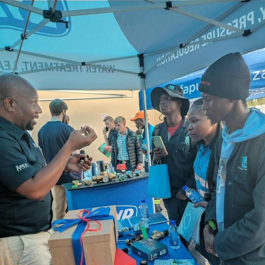 Maluti TVET College Students Learning About Water Treatment Fittings Maluti TVET College students being shown plumbing fittings by an exhibitor at a water treatment and pressure regulation expo stand