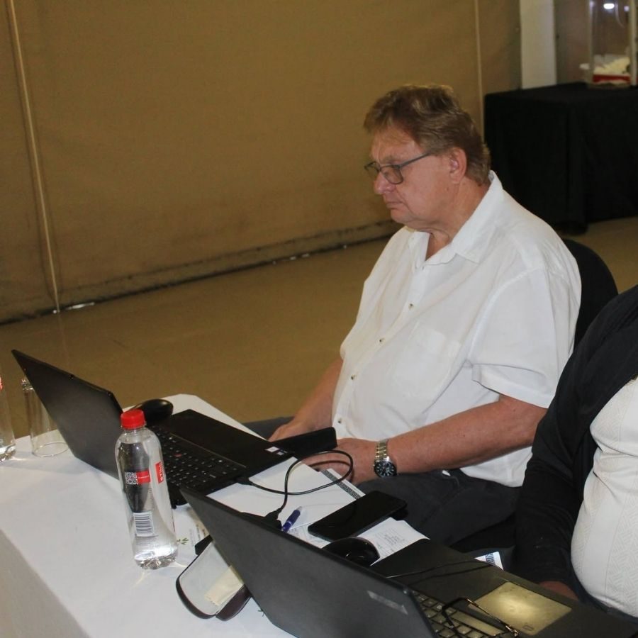 Official Working on Laptop at Mopani South East TVET College Event Man in white shirt seated at a table working on laptops during a Mopani South East TVET College meeting or ceremony