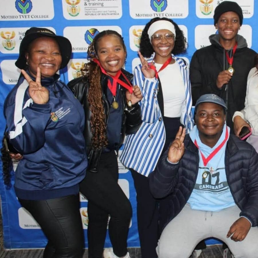 Motheo TVET College Students Celebrating with Medals Motheo TVET College students showing peace signs and wearing medals in front of a Motheo TVET College branded photo wall
