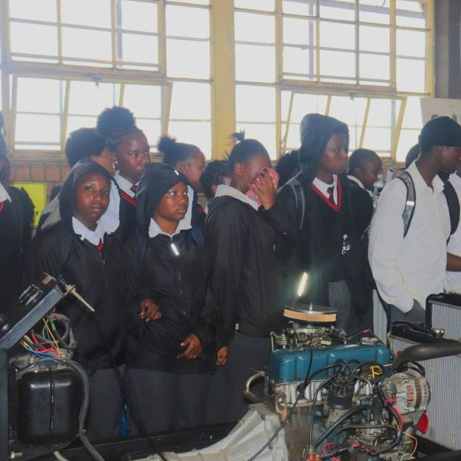 School Pupils Touring Nkangala TVET College Motor Workshop School pupils in uniform viewing an engine and vehicle parts during a workshop tour at Nkangala TVET College