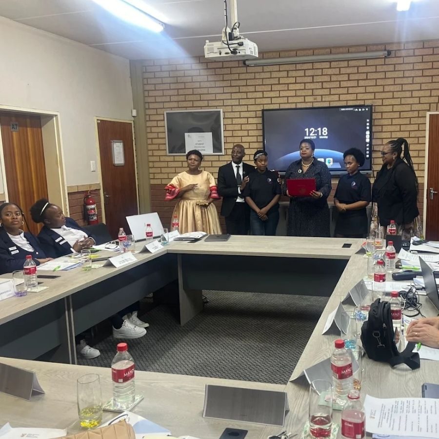 Orbit TVET College Award Handover Meeting Staff present a certificate during a formal handover at an Orbit TVET College boardroom meeting.