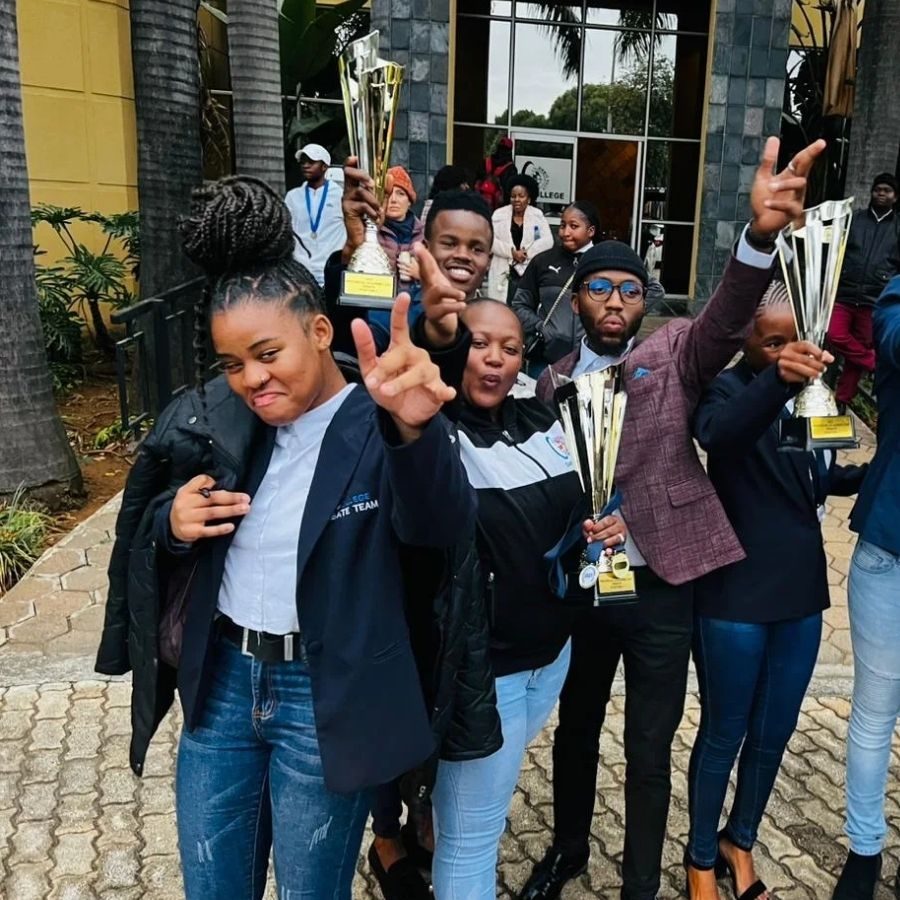 Orbit TVET College Debate Team Celebrates Trophies Orbit TVET College debate team members celebrate outdoors while holding trophies after a competition win.