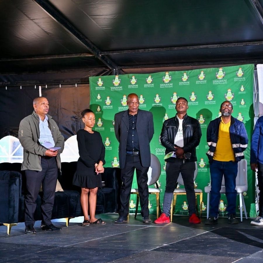 Sekhukhune TVET College Officials on Stage Panel Officials stand on stage in front of a Sekhukhune District Municipality backdrop at an event linked to the college.