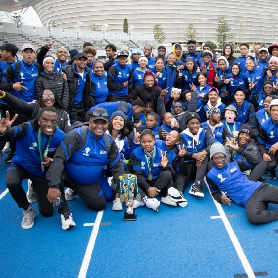 South Cape TVET College Athletics Team Trophy Win A large group of South Cape TVET College athletes celebrates with a trophy on the track at a large stadium.