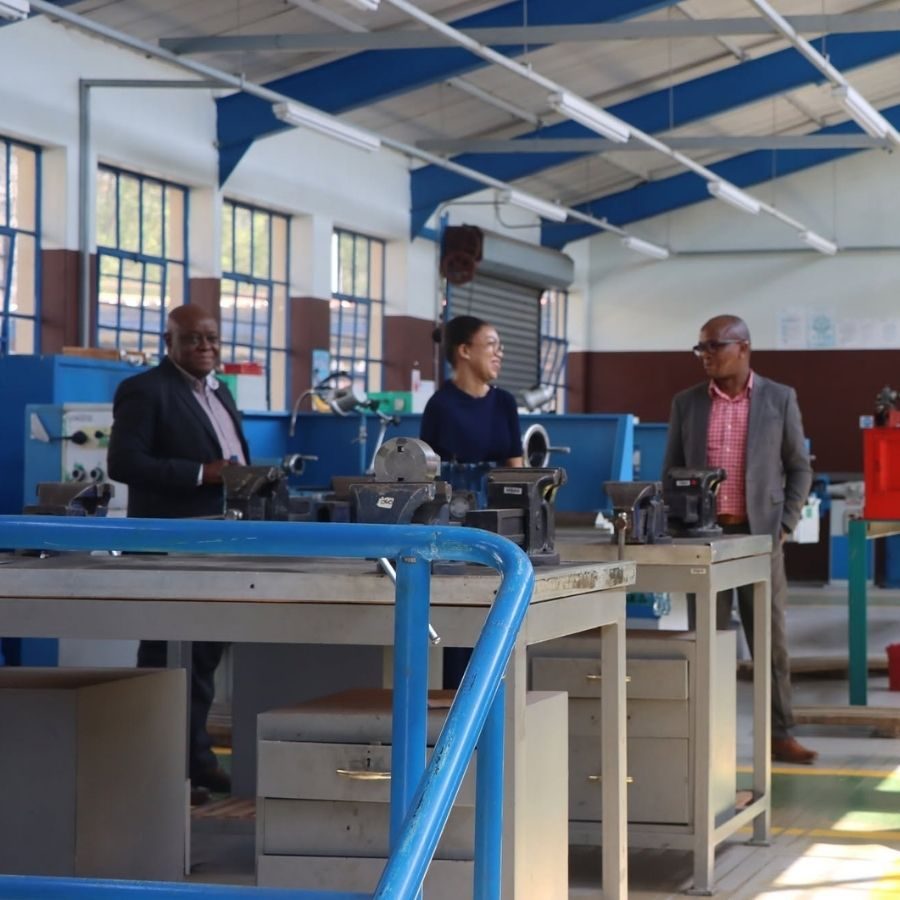 Tshwane South TVET College staff members chat beside workbenches and vices in a mechanical engineering workshop